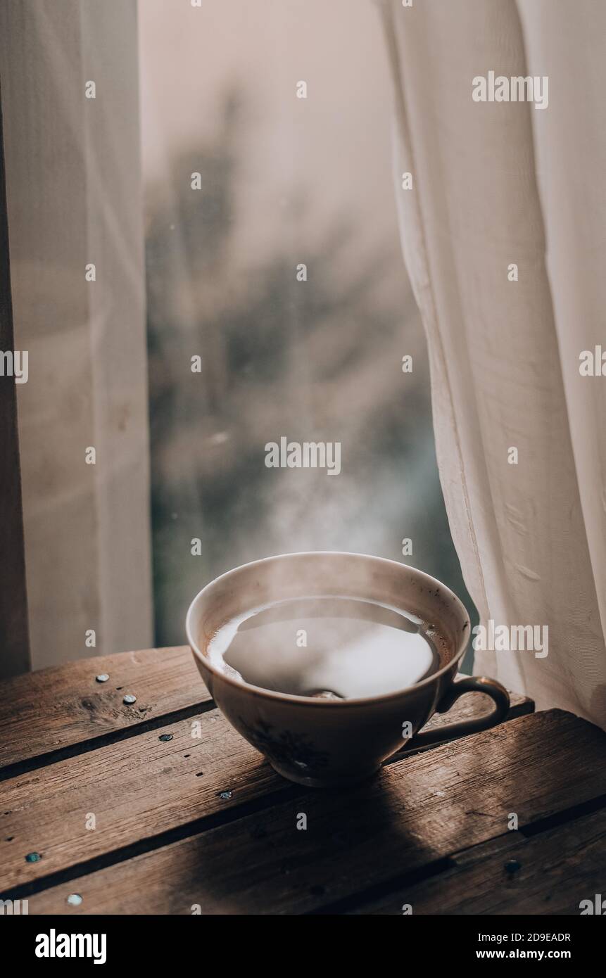 Cup of warm coffee on a wooden table by the window Stock Photo