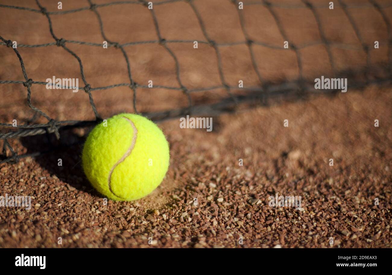 Tennis ball on clay and tennis net. Copy space for text. Stock Photo