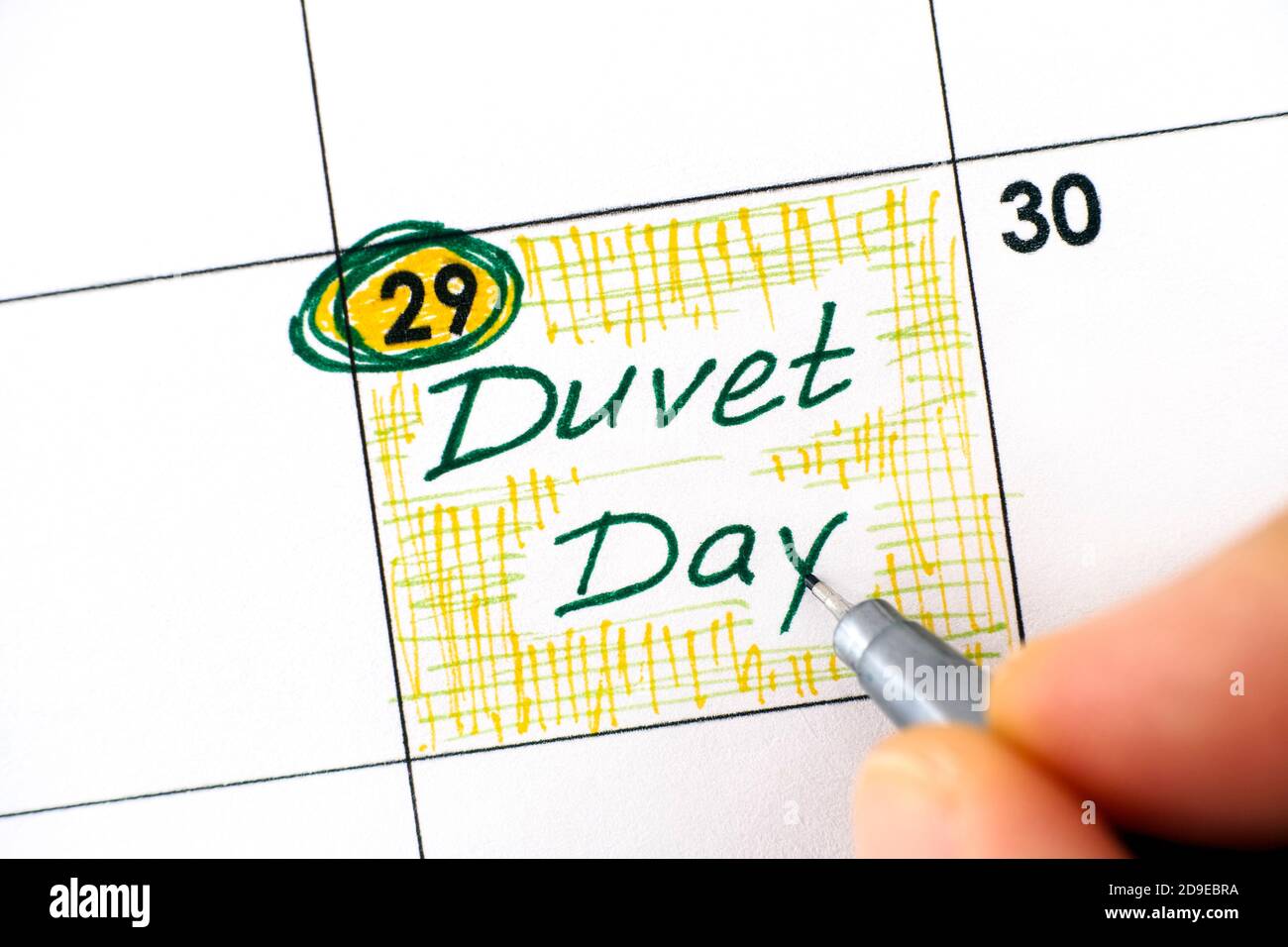 Woman fingers with pen writing reminder Duvet Day in calendar. Stock Photo