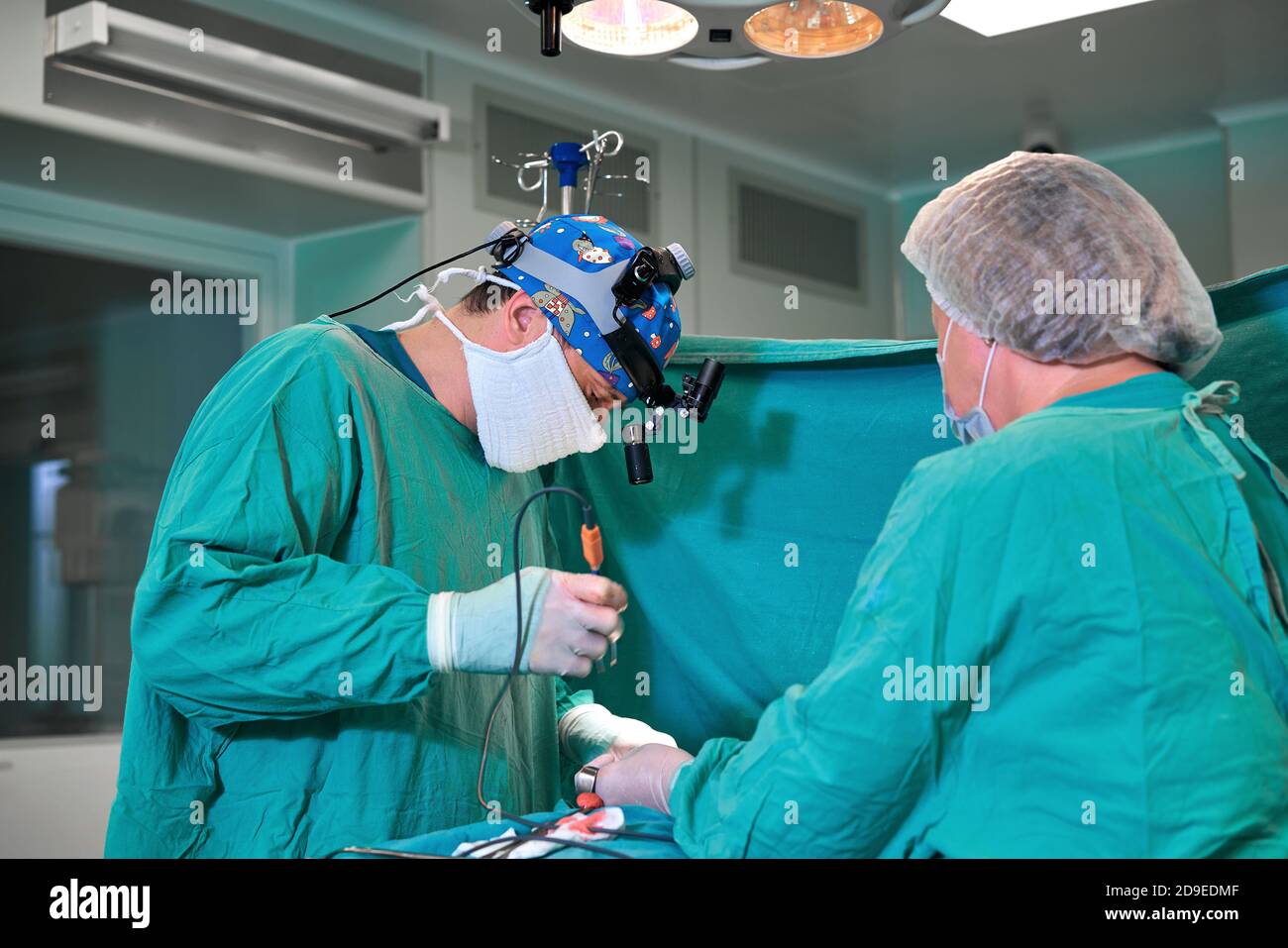 Surgeon and his assistant performing cosmetic surgery on nose in hospital operating room. Nose reshaping, augmentation. Rhinoplasty. Stock Photo