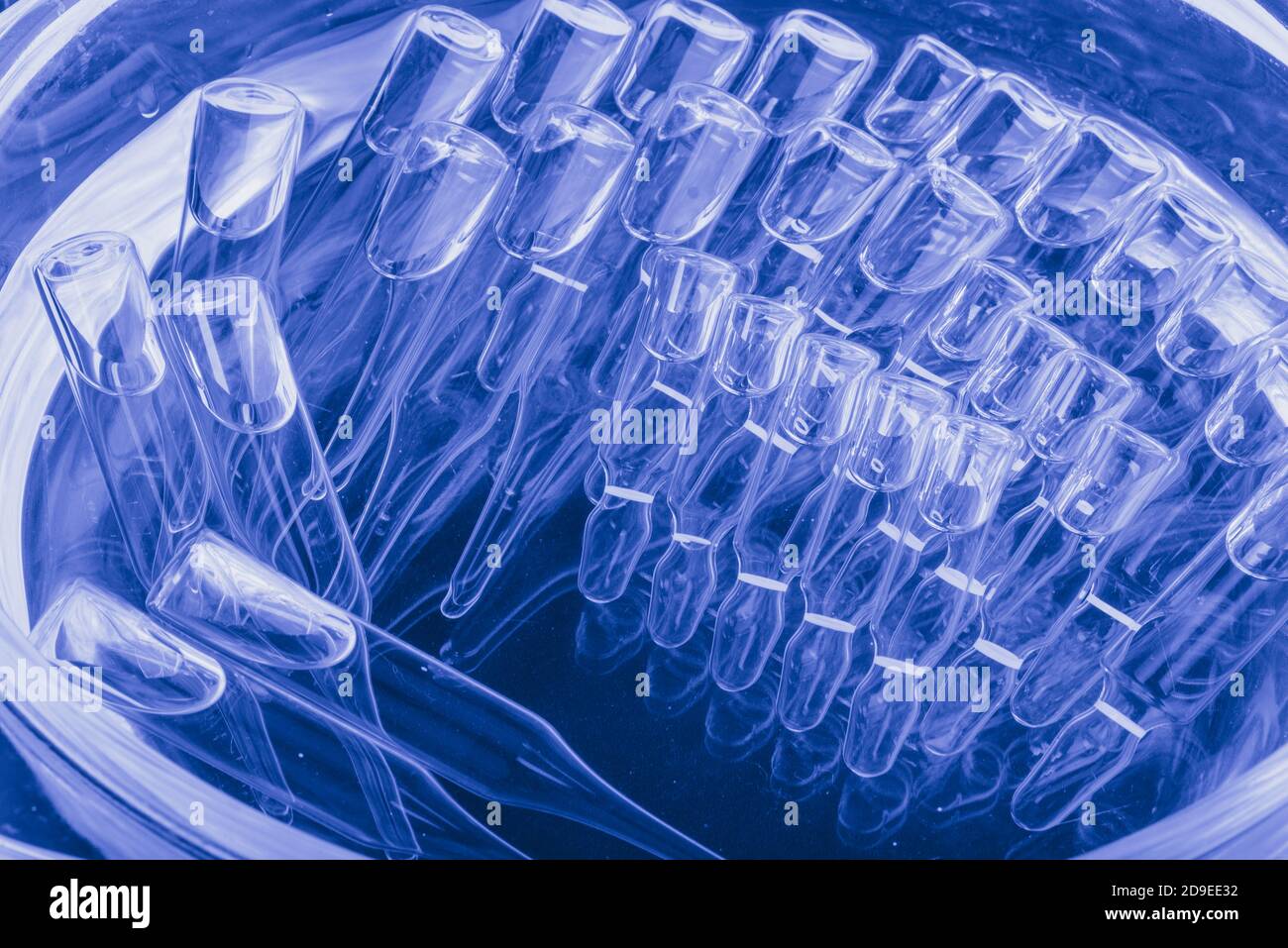 Glass medical ampoule vial for injection. Medicine is liquid sodium chloride with of aqueous solution in ampulla. Close up. Bottles ampule multicolor. Stock Photo