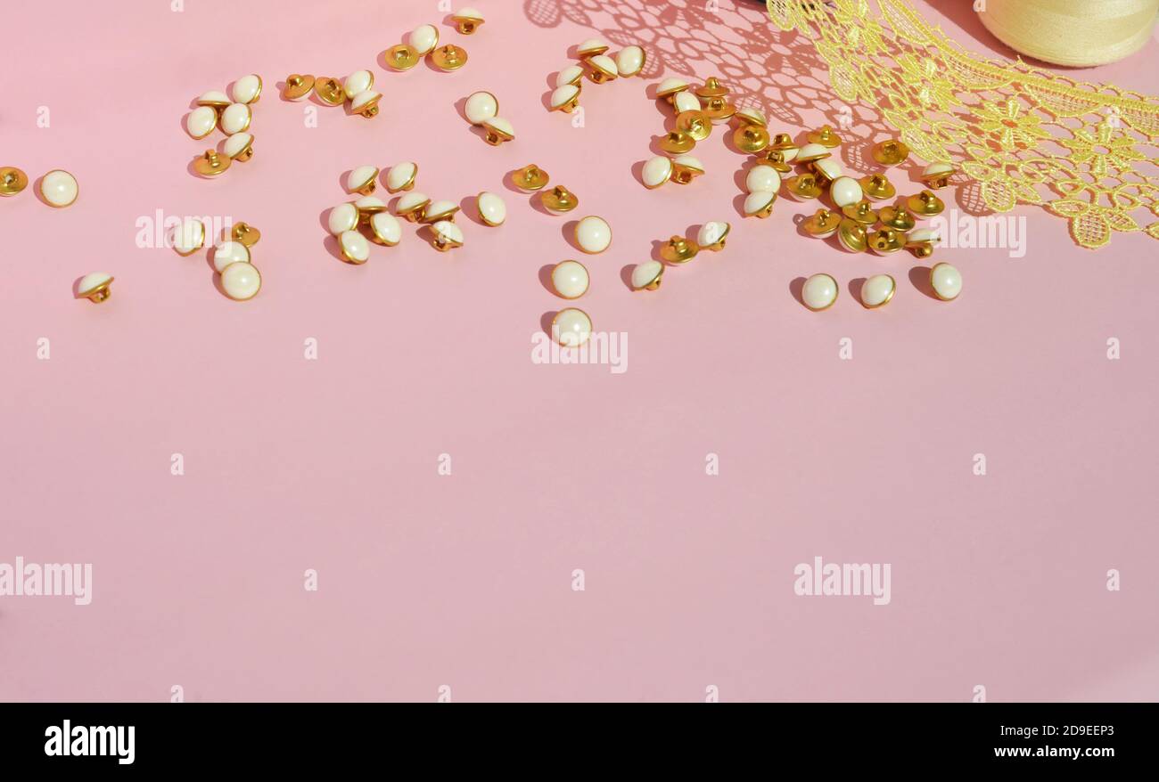 Small buttons on a pink background. Items for needlework. For sewing clothes. Sewing. Free space for text. Stock Photo