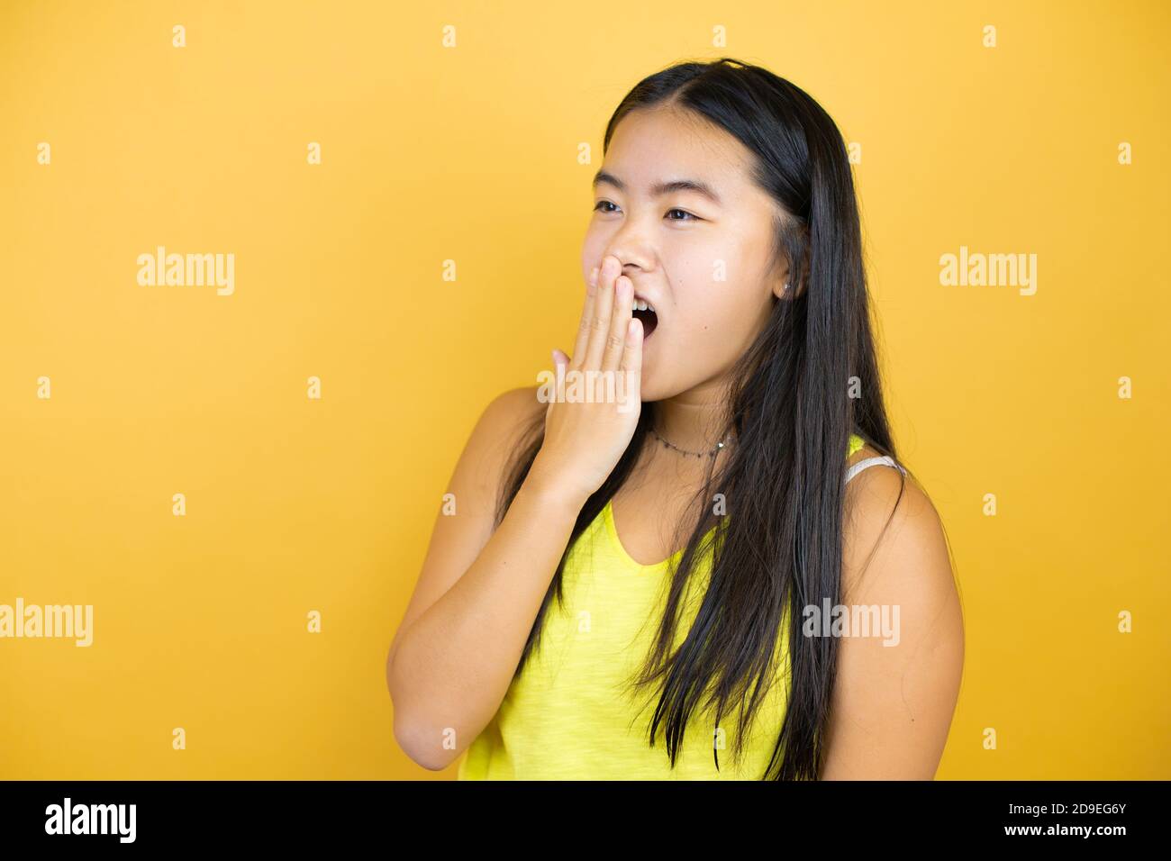 Young beautiful asian woman over yellow isolated background with her ...