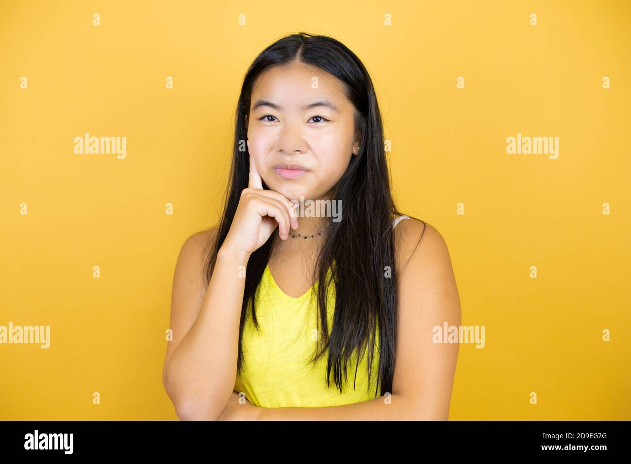 Young beautiful asian woman over yellow isolated background thinking ...
