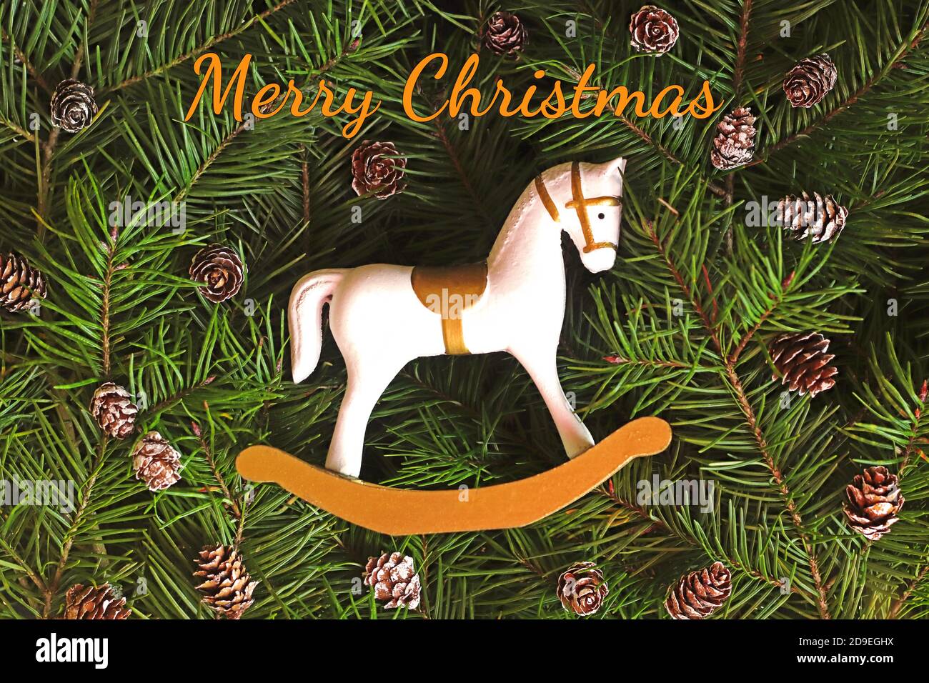 retro Christmas background with a small and cute rocking horse on fir branches and fir cones Stock Photo