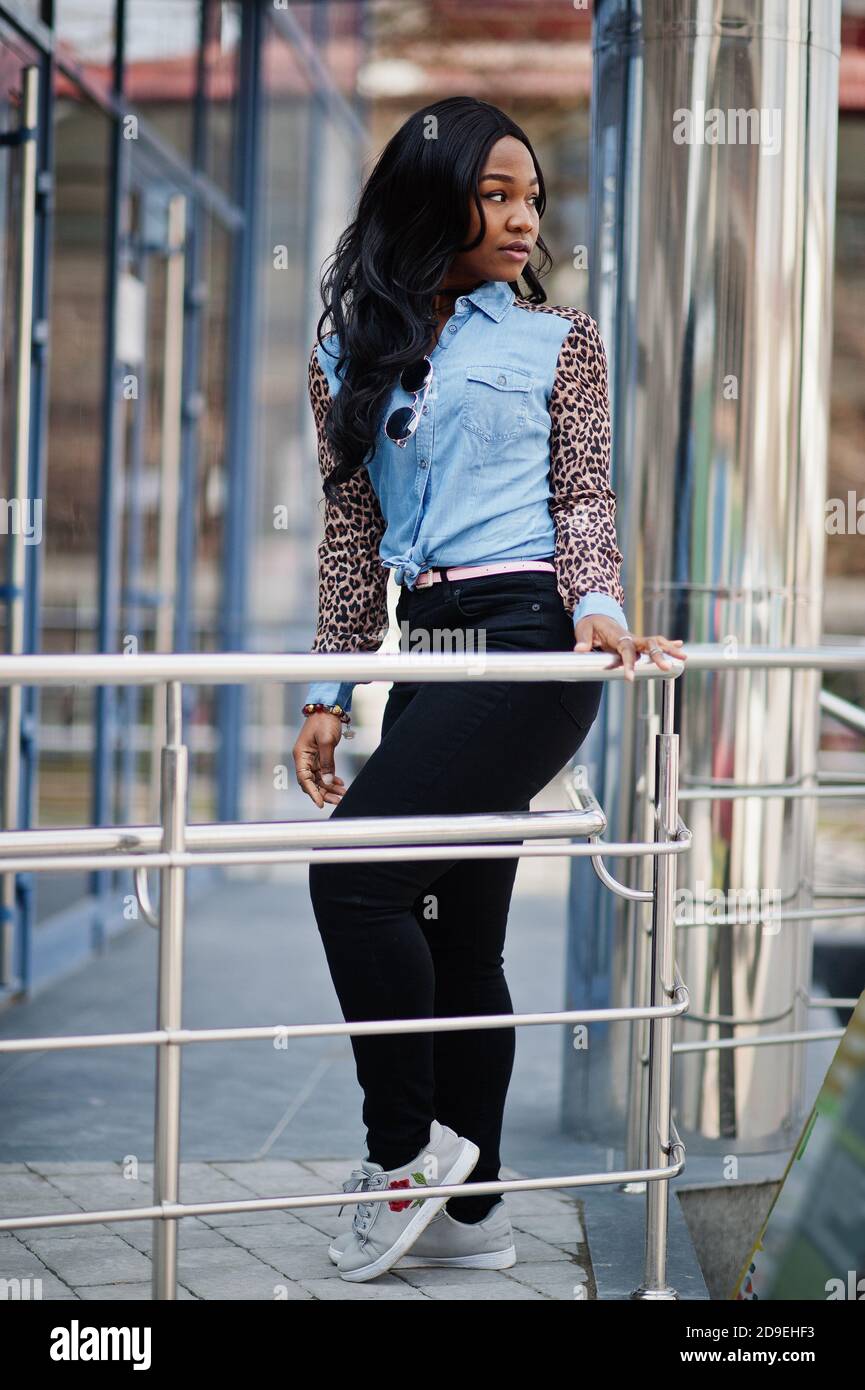 Hipster african american girl wearing jeans shirt with leopard sleeves  posing at street against modern office building with blue windows Stock  Photo - Alamy