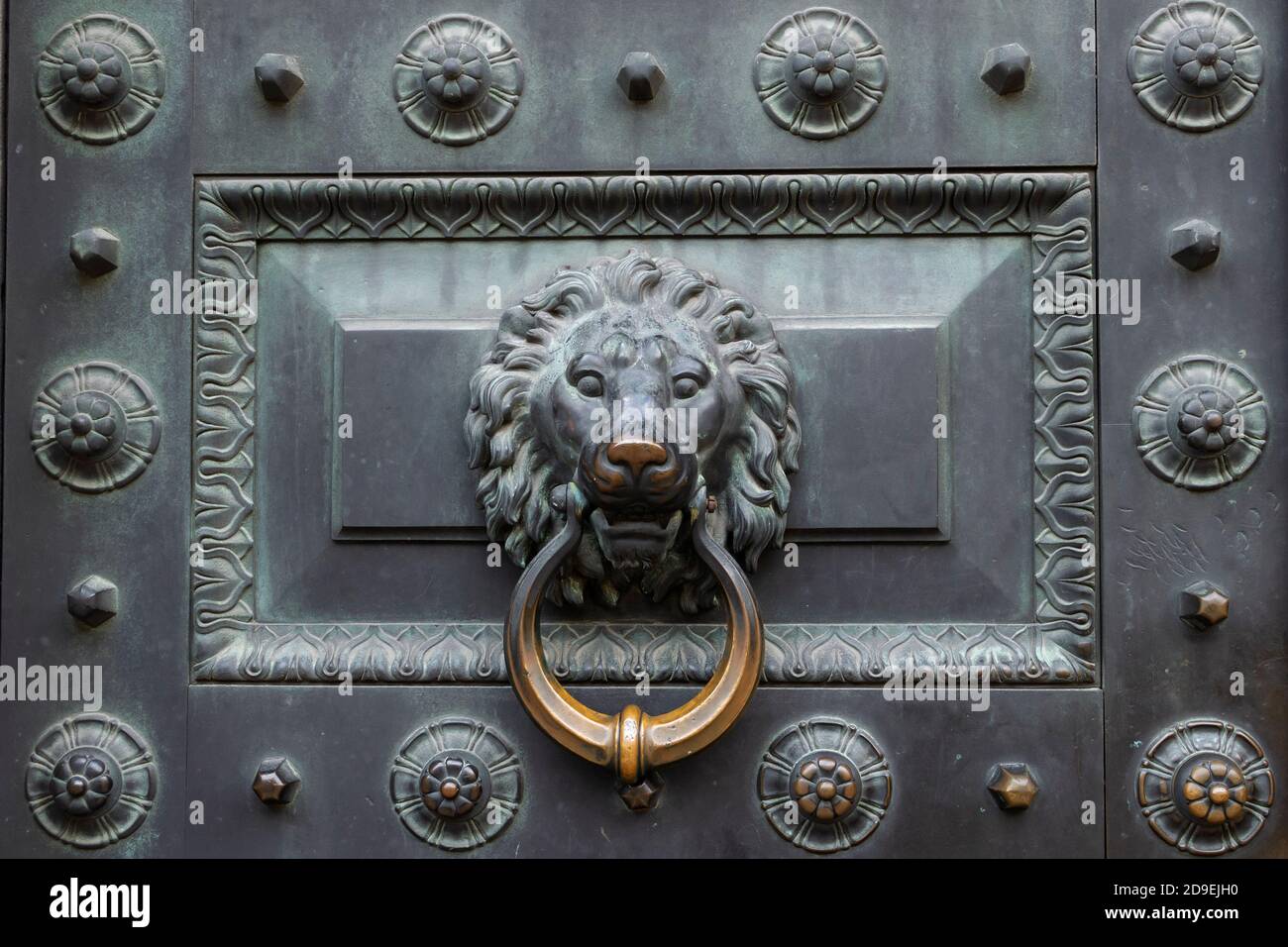 Antique bronze door knocking knob ring in the form of a lion's face on an old door. Stock Photo