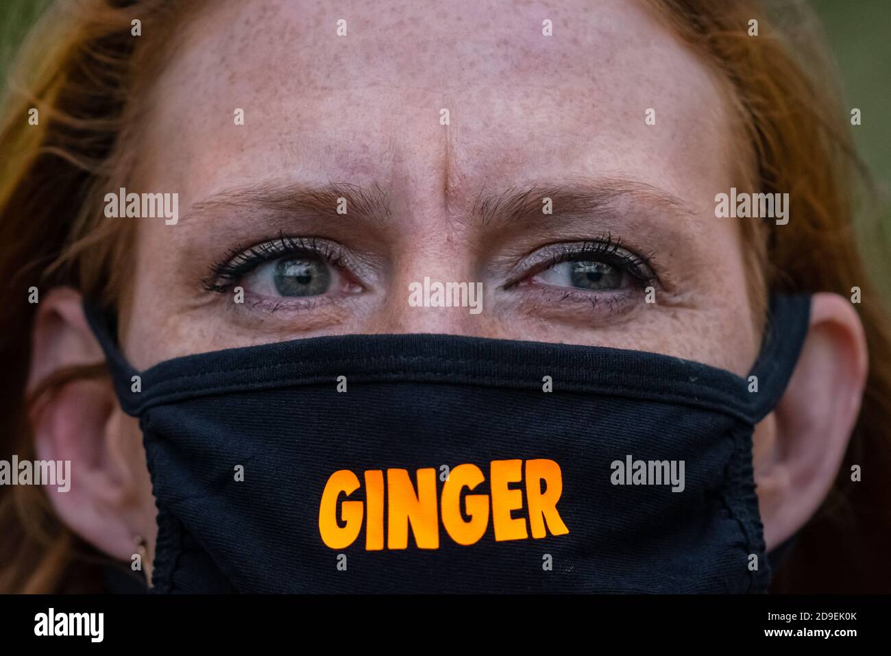 London, UK. 5th November, 2020. National Redhead Day. A red-headed lady passes through St. James' Park with a face mask entitled 'Ginger Lives Matter'. Celebrated annually on 5th Nov, National Redhead day would usually see a large gathering of 'gingers' from across the UK joining in celebration of the uniqueness of red hair. Credit: Guy Corbishley/Alamy Live News Stock Photo