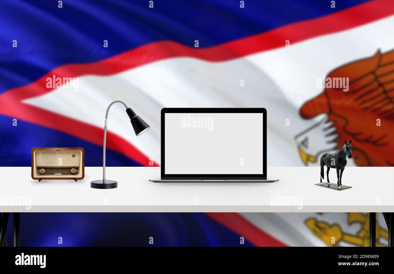 American Samoa national flag background with workspace, desktop computer and office accessories on white modern table. Stock Photo
