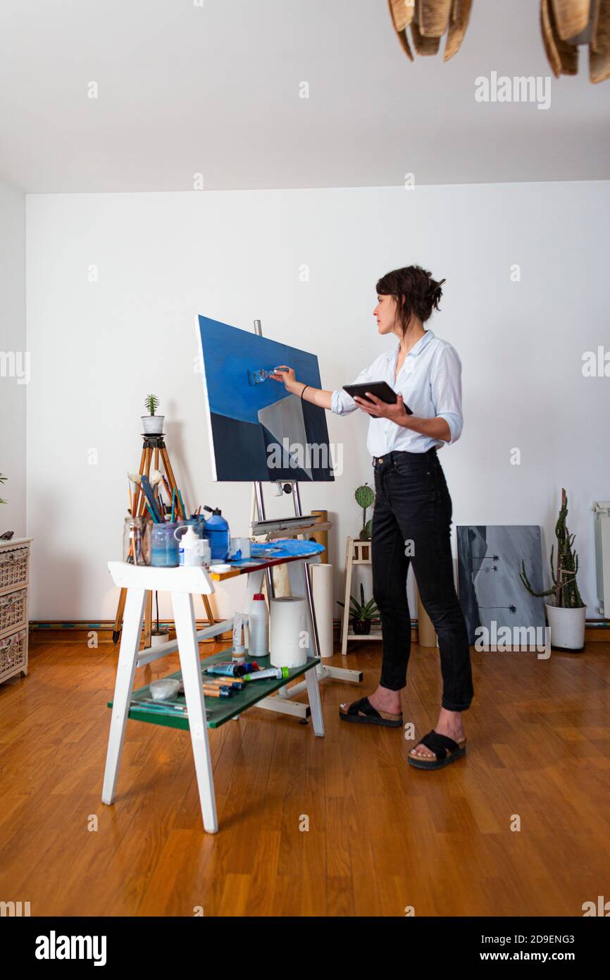 The young painter stands in her home studio and copies the sketch from ...