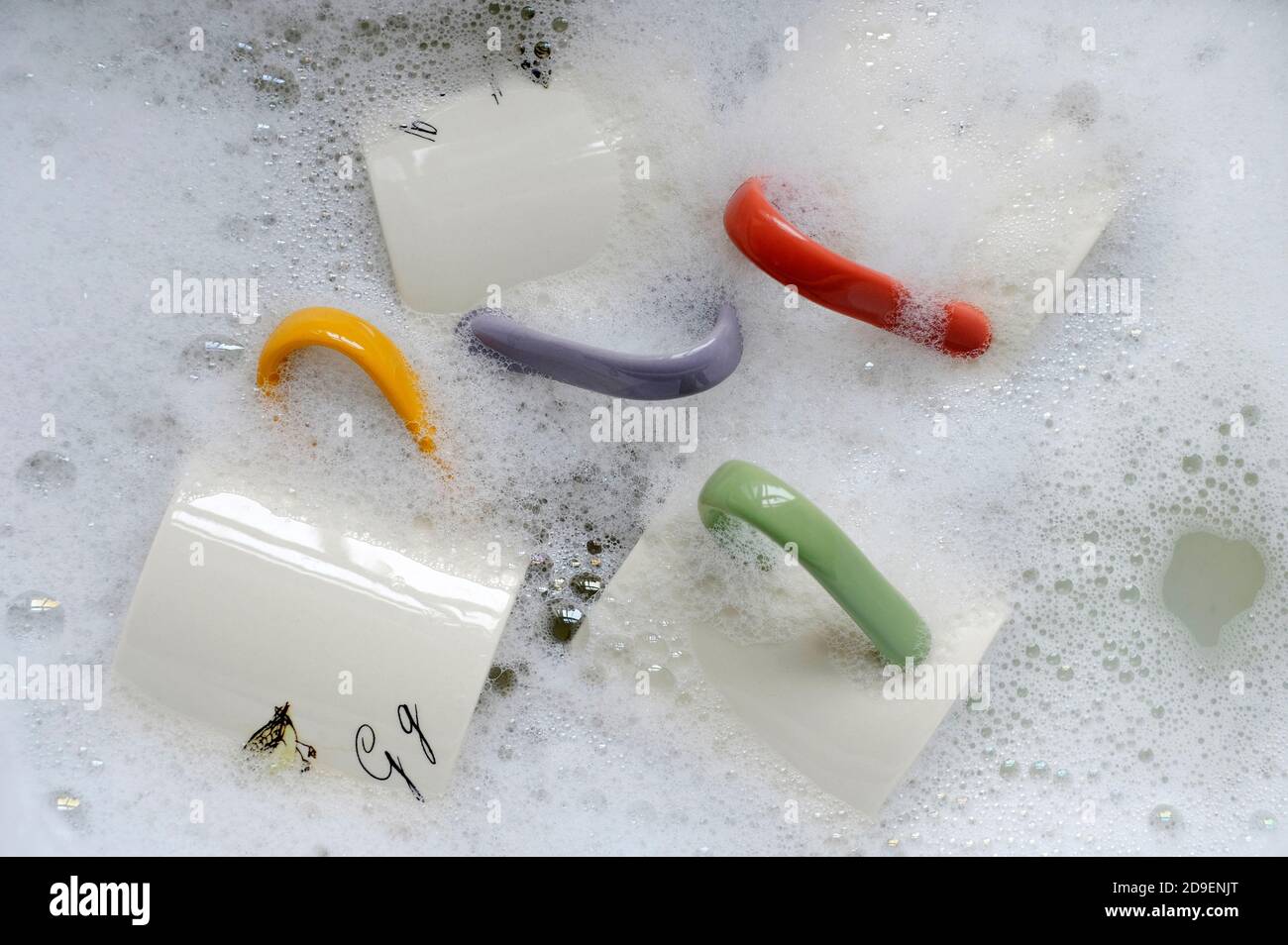 mugs in washing up bowl with soap suds Stock Photo
