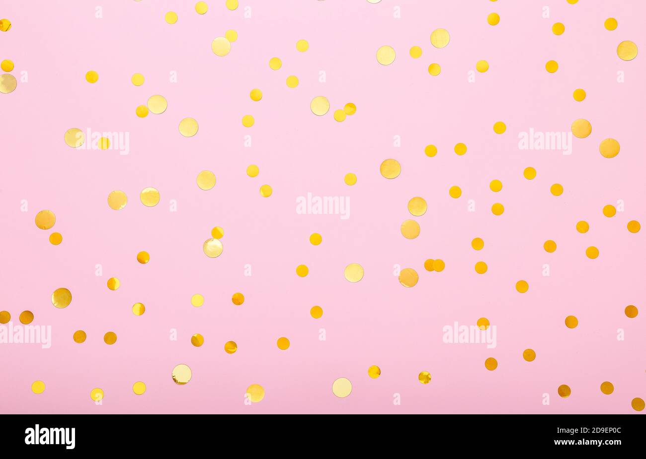 Gold confetti sparkles on pink background. Flat lay, top view festive backdrop. Celebration concept. Stock Photo