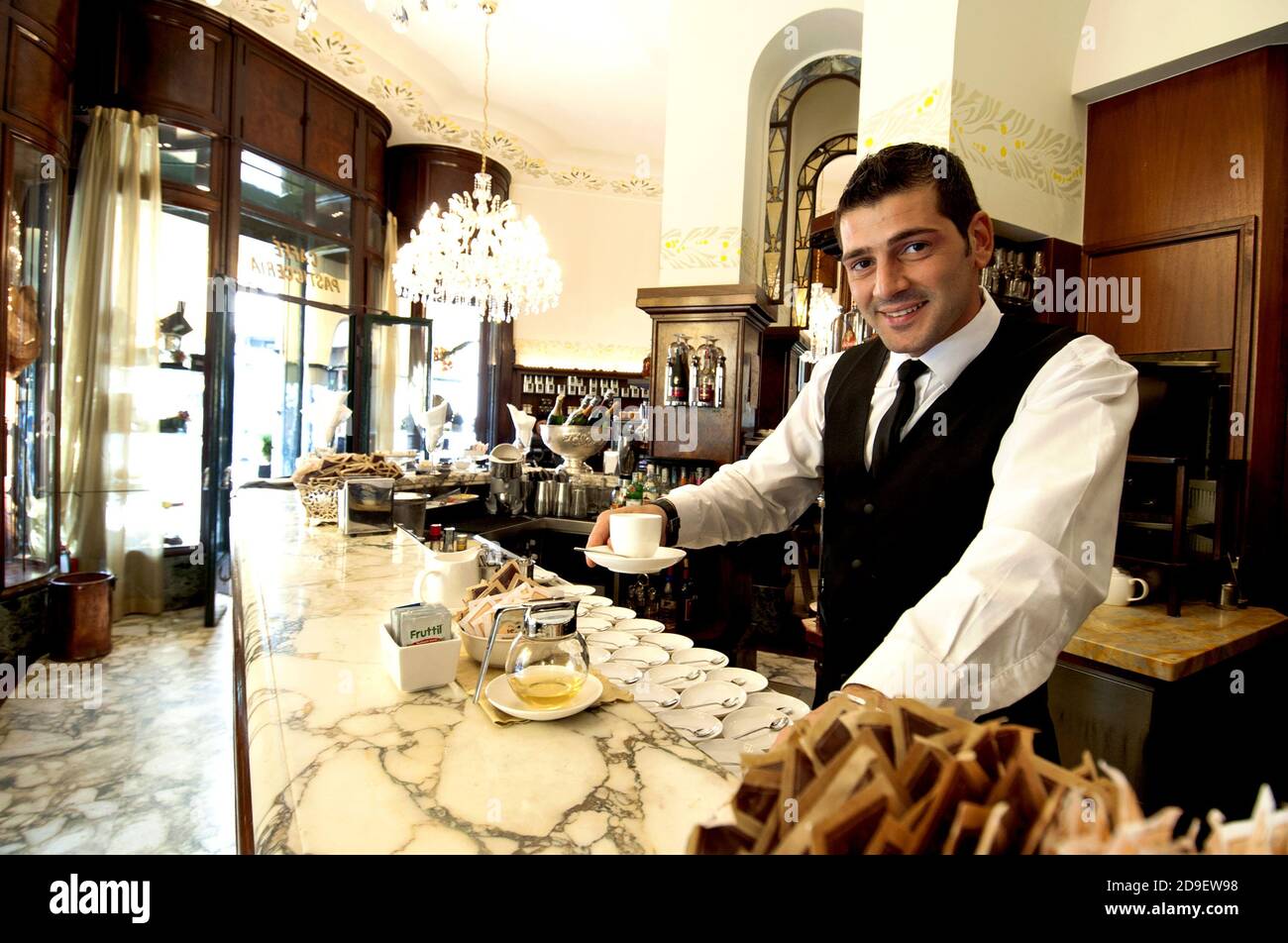 Italian barman serving an espresso coffee in an historical cafeteria of Milan, Italy. Stock Photo