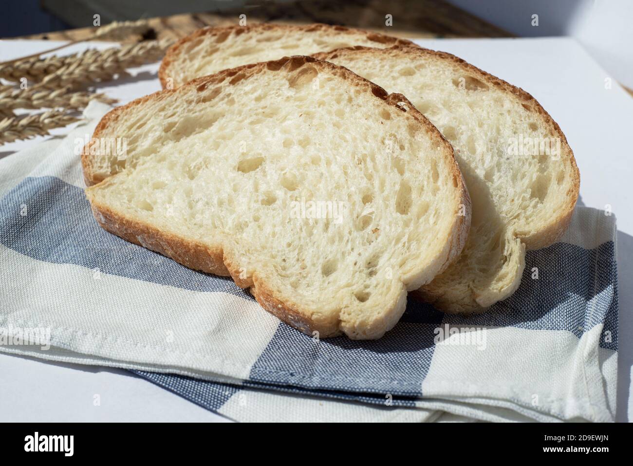 Three pieces of wheat bread on a kitchen towel. Wheat ears are near. Stock Photo