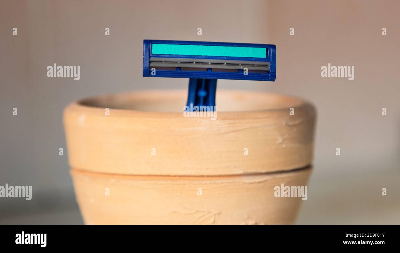 A blue razor stands in a clay mug in the bathroom Stock Photo - Alamy