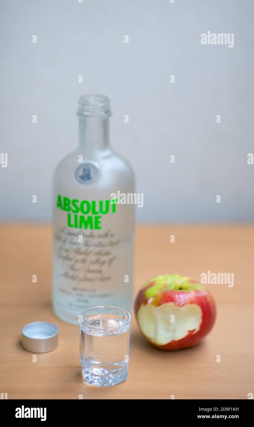 A bottle, one small glass Absolut Vodka and apple on the wooden table.Warsaw, Poland. 05.11.2020 Stock Photo