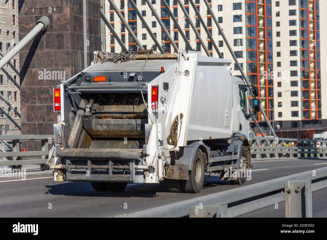 Garbage truck driving on the highway in the city, back view Stock Photo