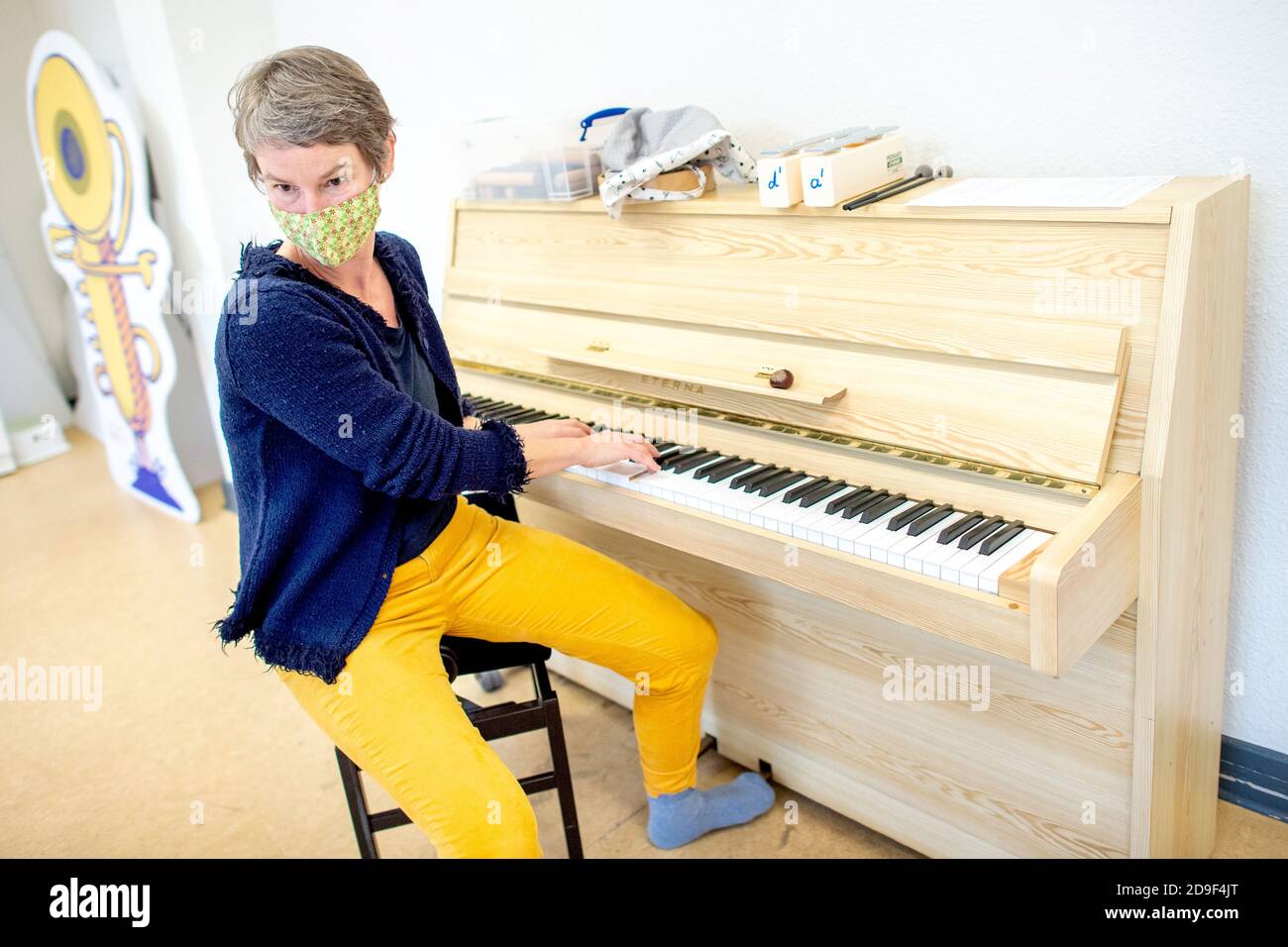 Hanover, Germany. 03rd Nov, 2020. Music teacher Annette Hartung plays a  piano during a lesson in early musical education at the municipal music  school, wearing a mouth-and-nose cover. Because they are classified