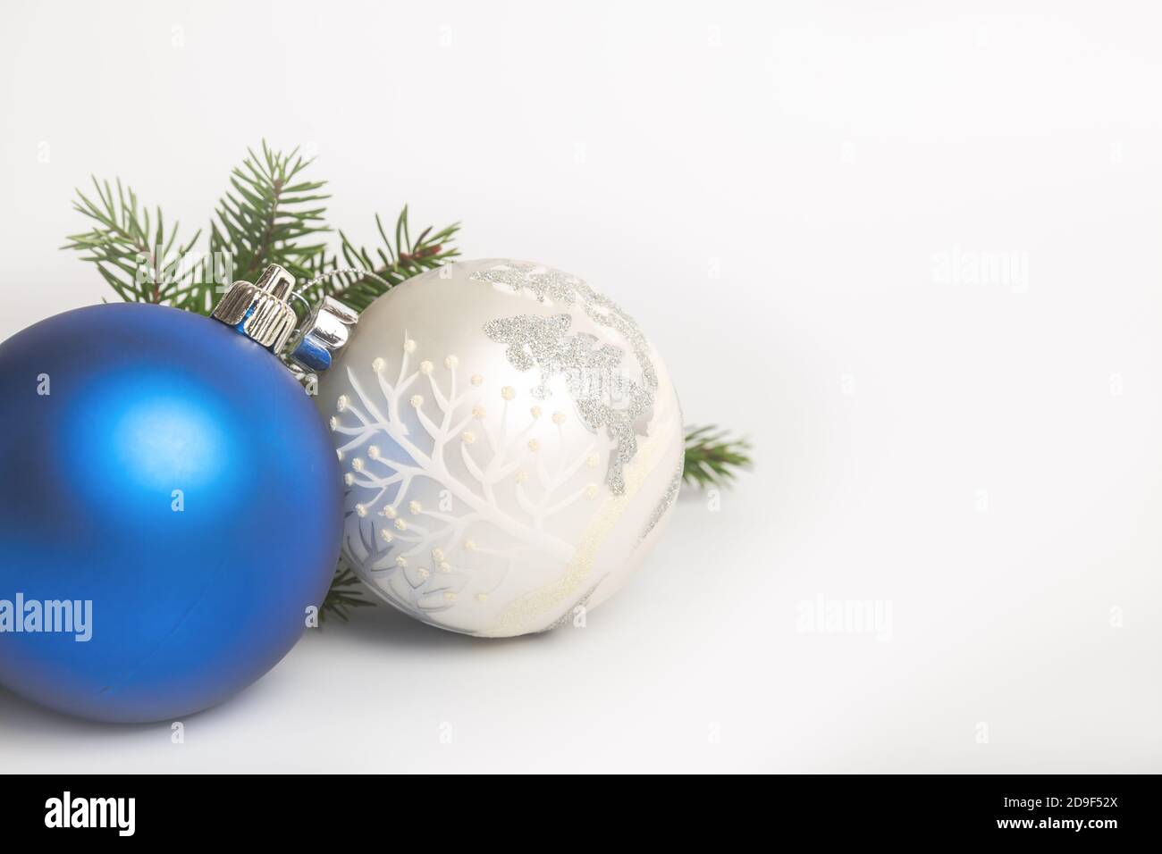 Two Christmas balls and branch of spruce close up on white background ...