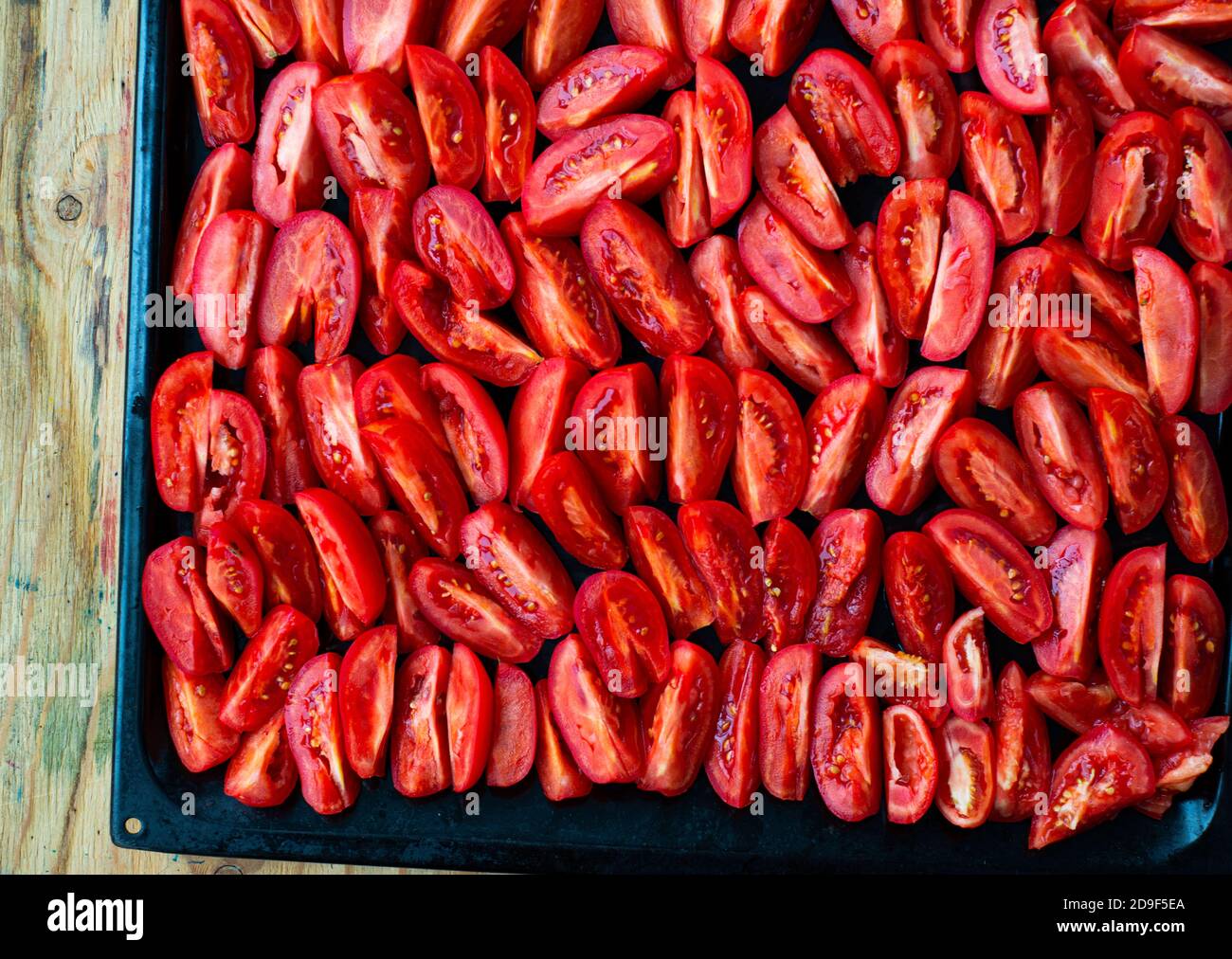 Tomatoes cut into wedges on a black pan. Tomato dishes. Tomato background. Stock Photo