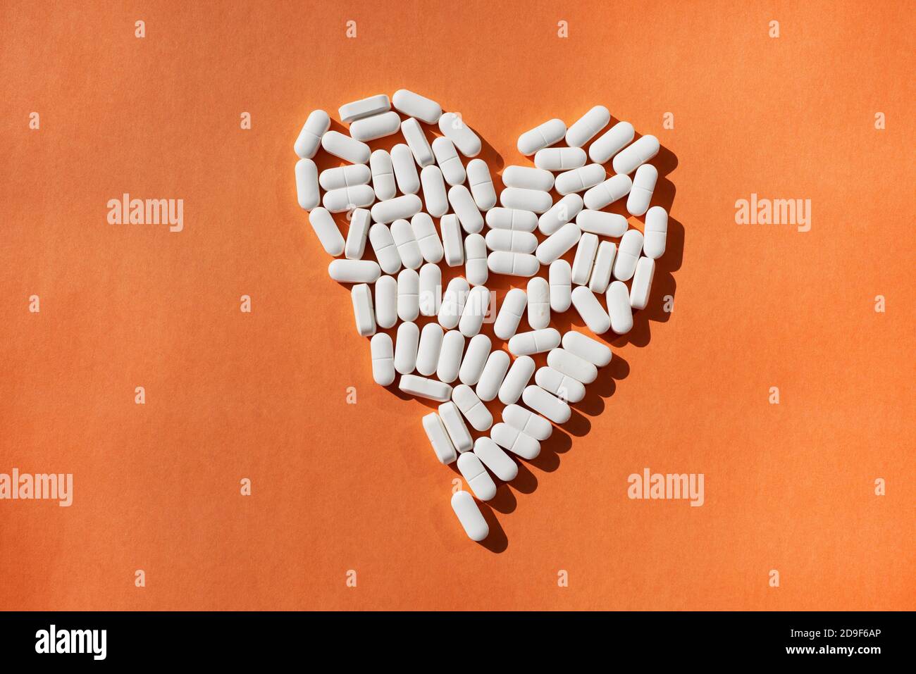 Minerals and trace elements for heart health. The shape of the heart is  laid out of white oval tablets on an orange background Stock Photo - Alamy