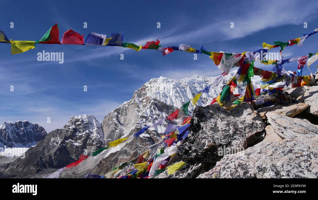 Viewpoint on the summit of mountain Kala Patthar with colorful Buddhist prayer flags flying in the strong wind and snow-capped Himalayan mountains. Stock Photo