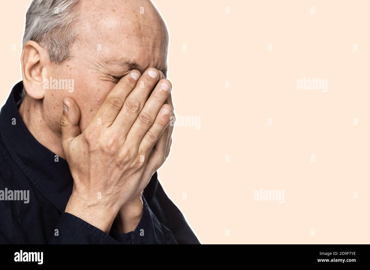 Elderly man suffering from a headache. Man covers his face with his ...