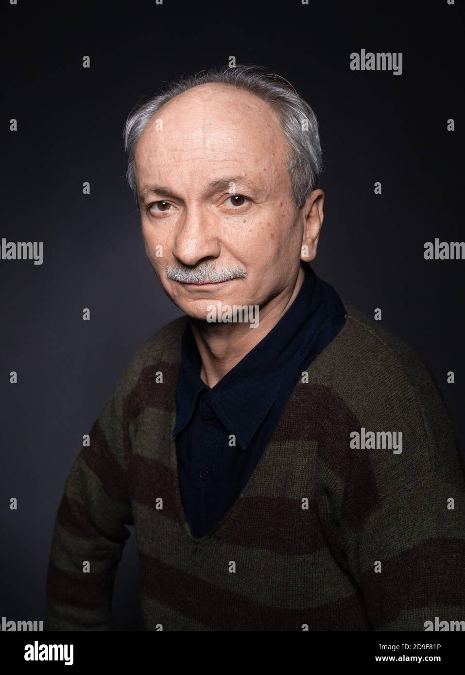 Studio portrait of an elderly tired man on a dark background. Looks ...