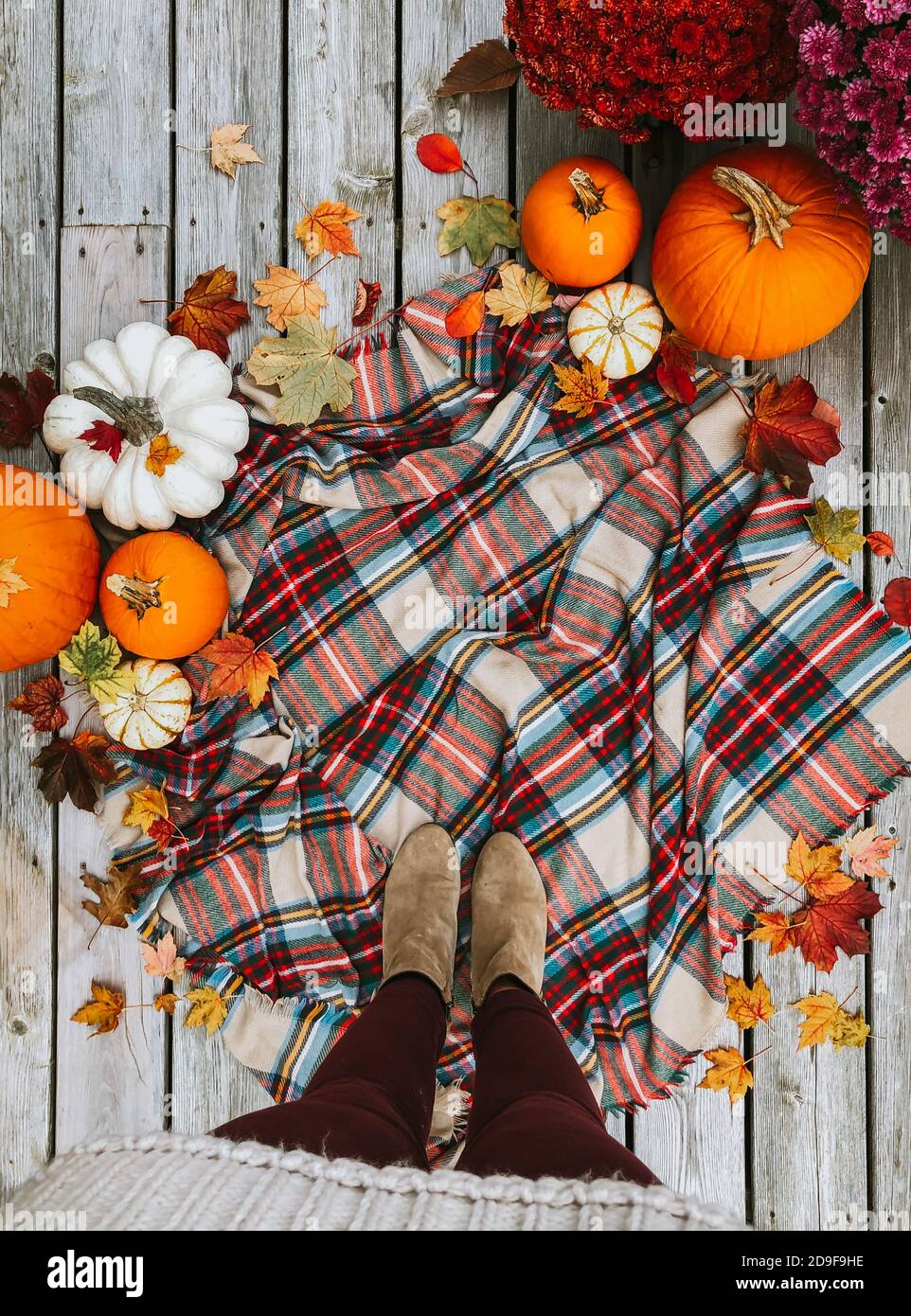 Overhead view of woman's feet on plaid scarf surrounded by fall items. Stock Photo