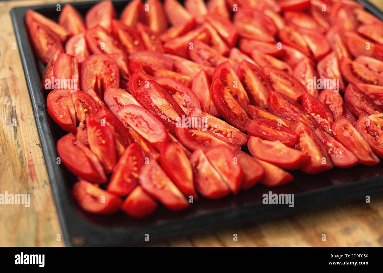 Tomatoes cut into wedges on a black pan. Tomato dishes. Tomato