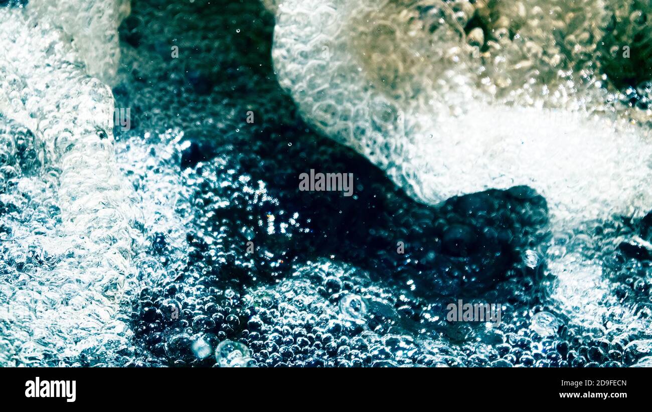 Water backgrounds with foam spray fast flow. The water in mad flows with droplets and whirlpools
