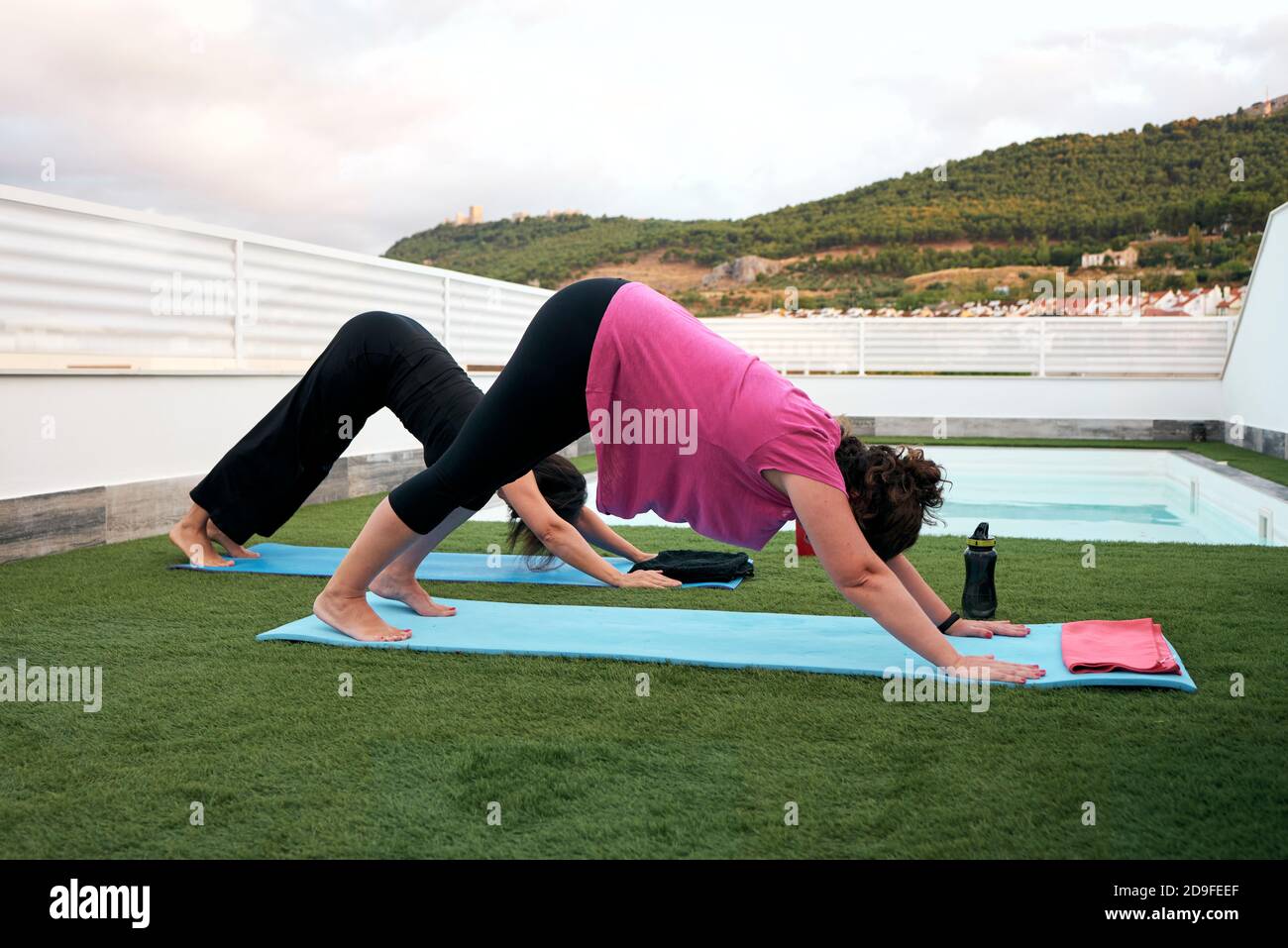 women do yoga on the terrace of the house, face down dog posture Stock Photo