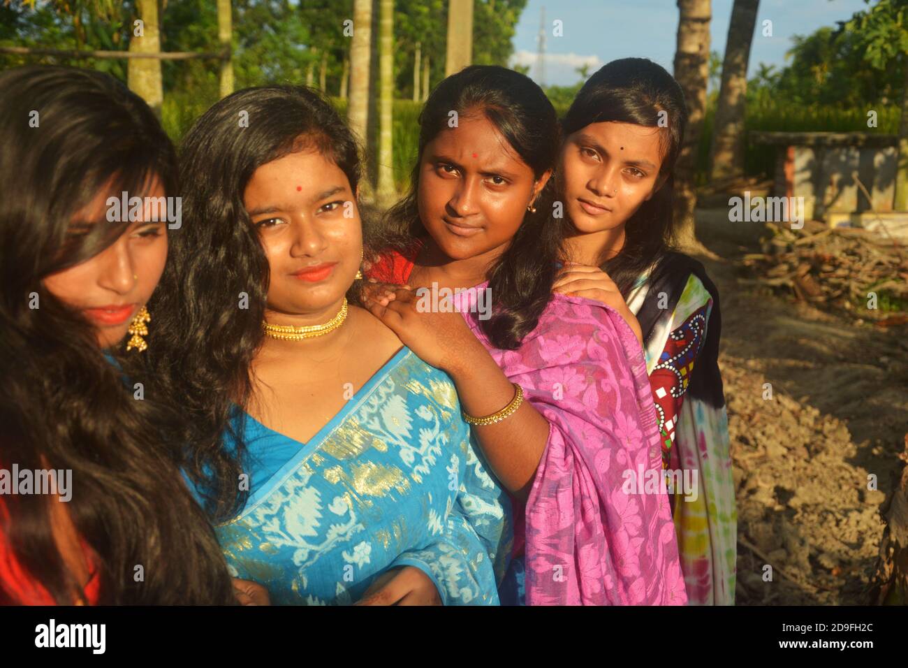 Close up of four beautiful teenage Indian Bengali girls with long dark hair wearing sari and jewelleries like golden earrings necklace, elective focus Stock Photo