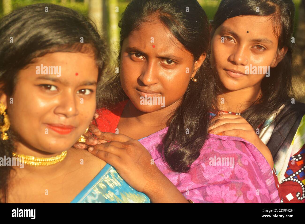 Close up of four beautiful teenage Indian Bengali girls with long dark hair wearing sari and jewelleries like golden earrings necklace, elective focus Stock Photo