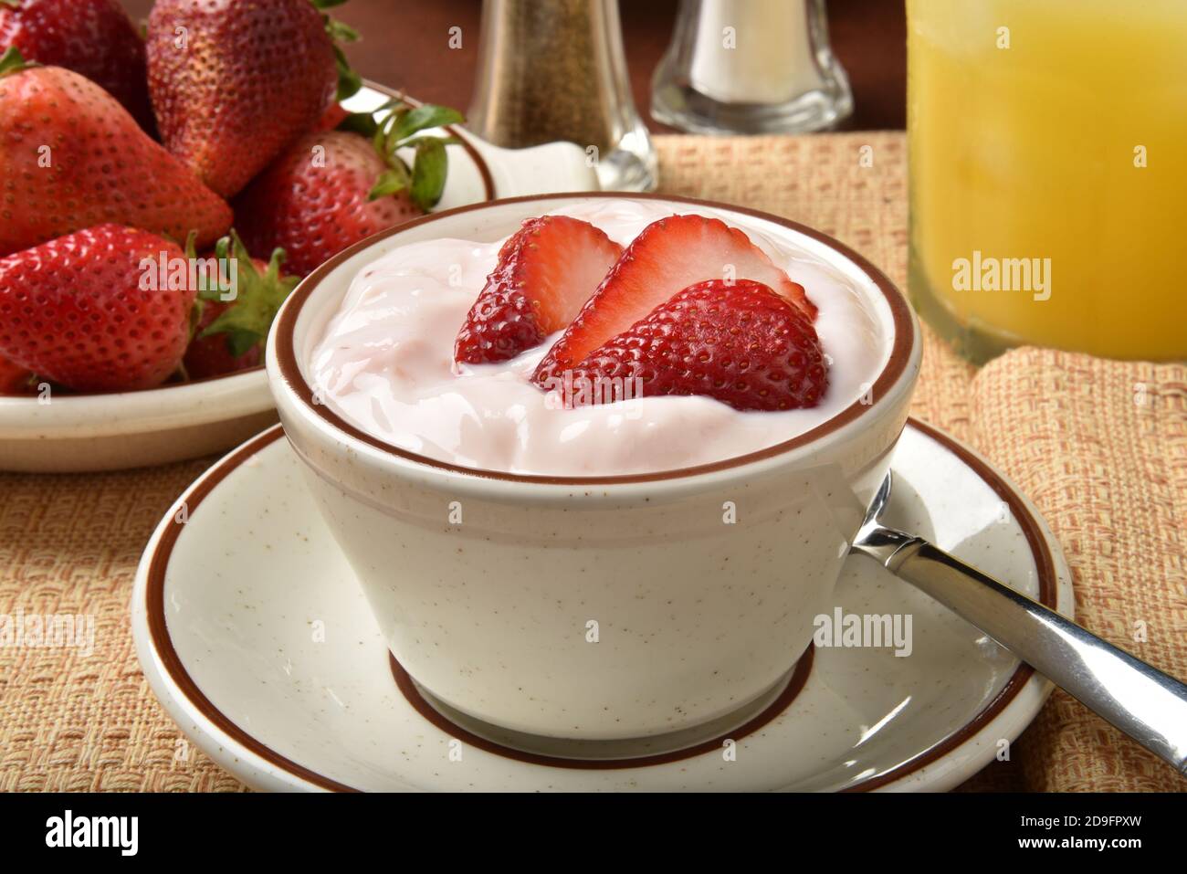 A bowl of strawberry yogurt with a glass of orang ejuice Stock Photo
