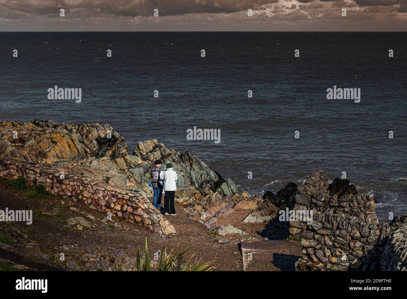 Everyday life. Old couple looking at the sea from rocky beach. Stock Photo