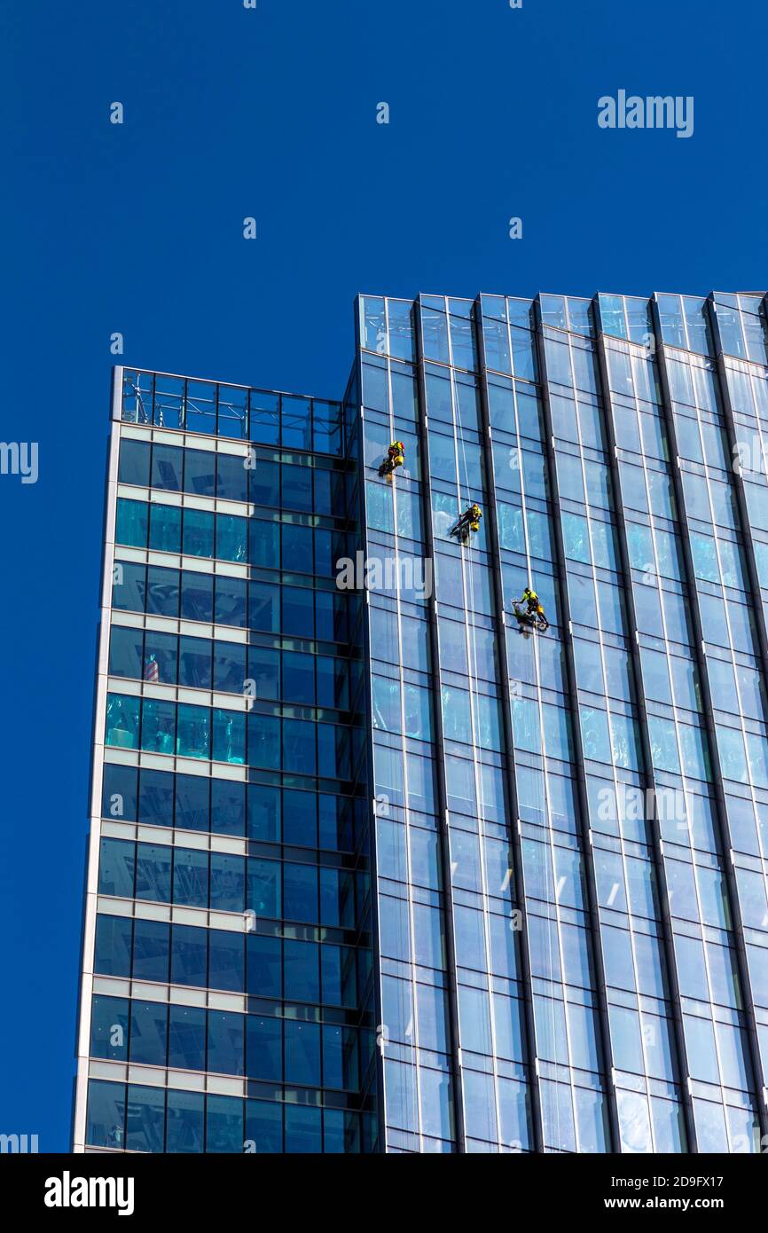 Window cleaners abseiling from a contemporary glass skyscraper cleaning windows, Warsaw, Poland Stock Photo