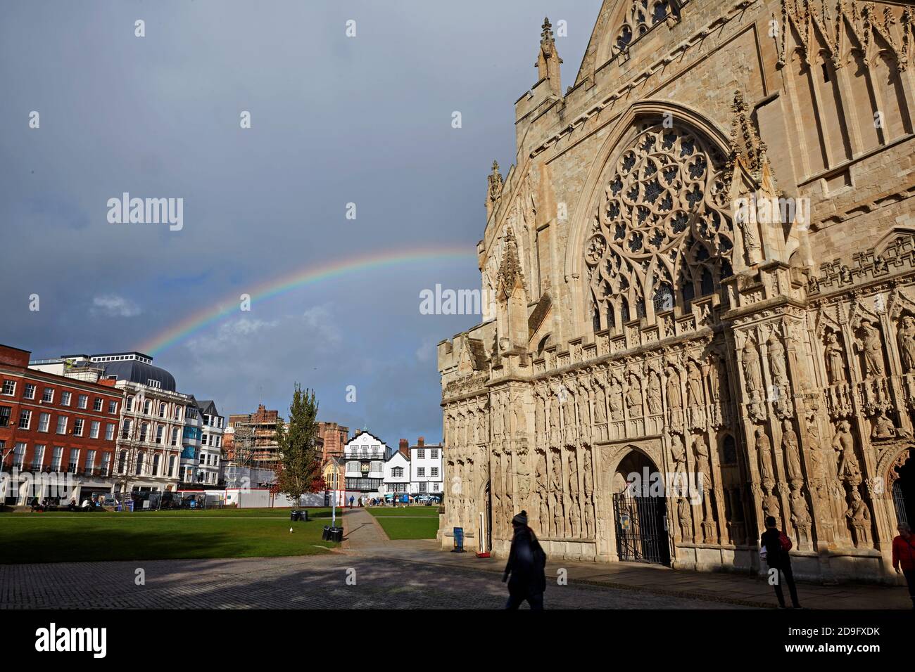 Facade of Exeter Cathedral with Central Exeter with rainbow in background Stock Photo