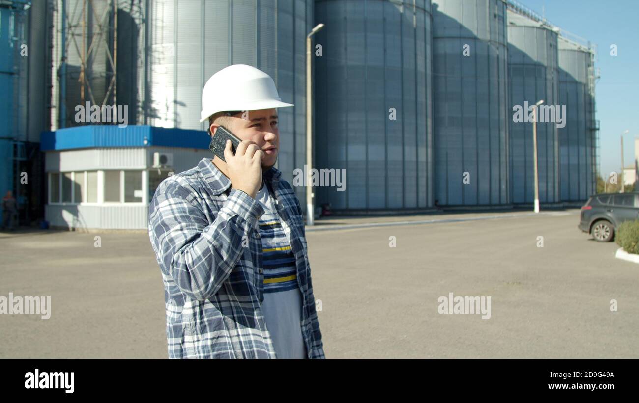 Engineer talking on phone near grain elevator Stock Photo