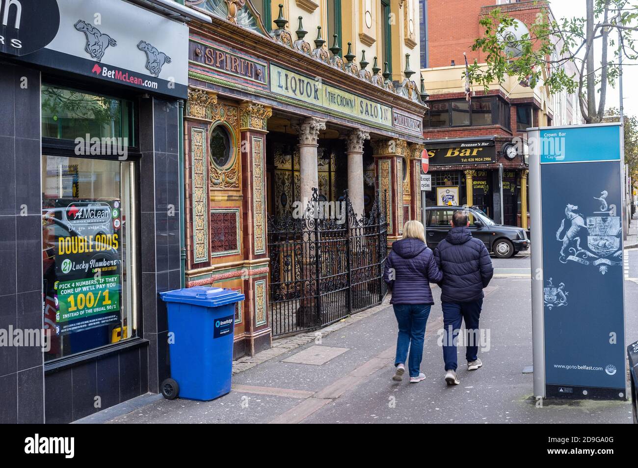 Belfast, Northern Ireland, UK, 4 November 2020: A couple walk past the closed Crown Bar. Bars in Northern Ireland have been closed from 16 October and are due to open on 15 November. Dr. Tom Black, Chair of the BMA, Northern Ireland has questioned the wisdom of relaxing the lock down on this date. Stock Photo