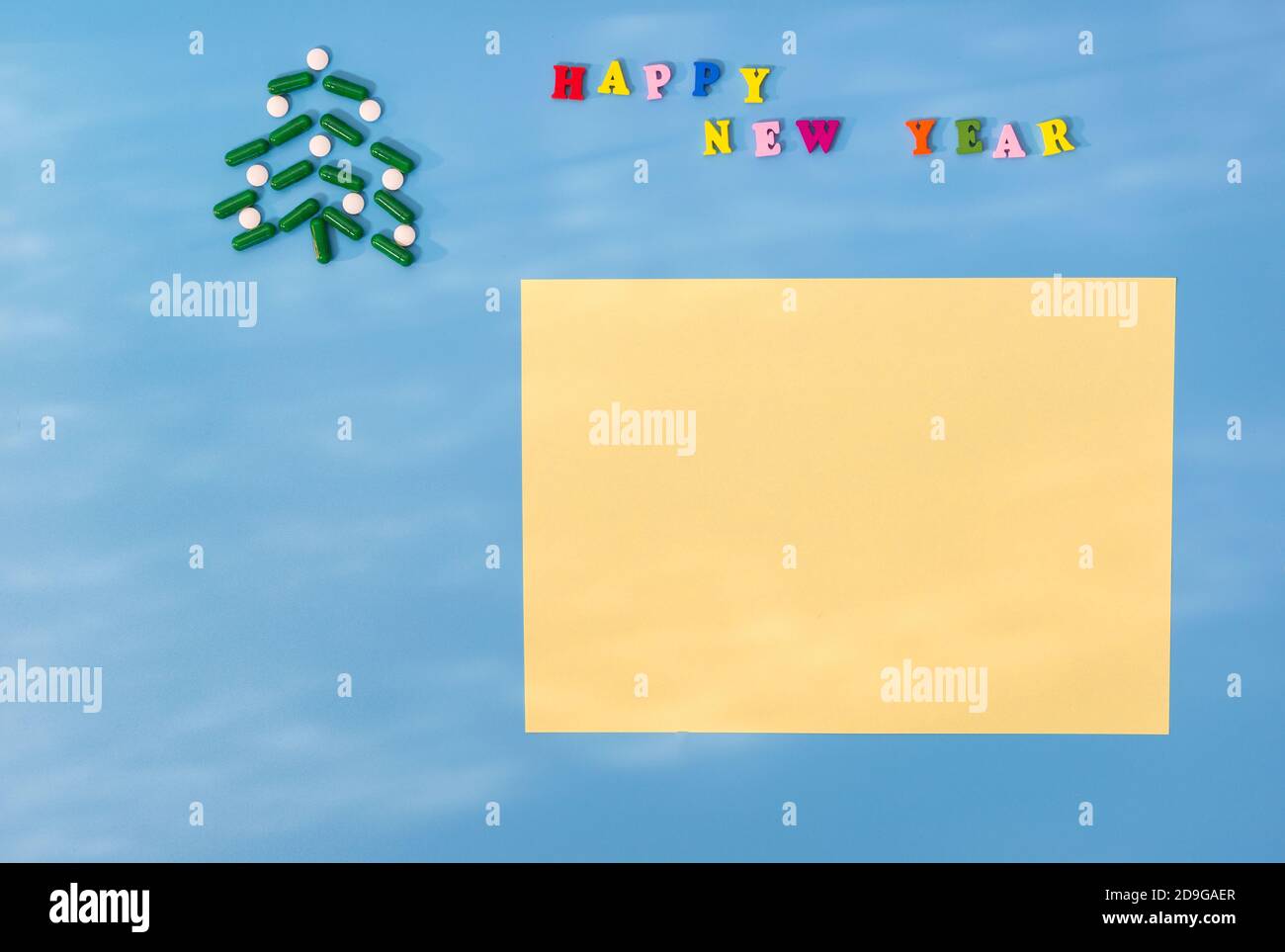 Christmas tree made of green capsules and white tablets and the inscription Happy new year. The sun's glare. The concept of a holiday during the perio Stock Photo