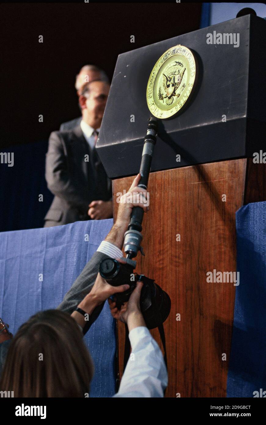 Two Bush 41 advance persons use a photographers 300MM f 2.8 lens and monopod (probably mine) to straighten the Vice Presidetntial seal on the podium before VP George W. Bush speaks in November 1988. Photo by Dennis Brack bb73 Stock Photo