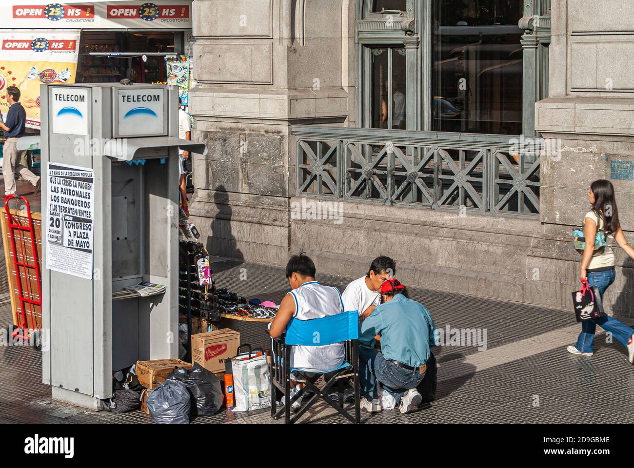 Buenos Aires, Argentiana- December 19, 2008: Ambulant sunglasses vendor sits near defunct telephone booth of Telecom at Retiro Station on Ave dr. Jose Stock Photo