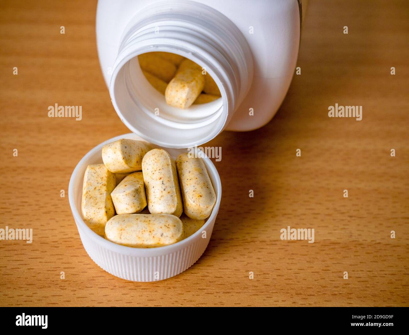 Herbal pills spilled in bottle cap Stock Photo