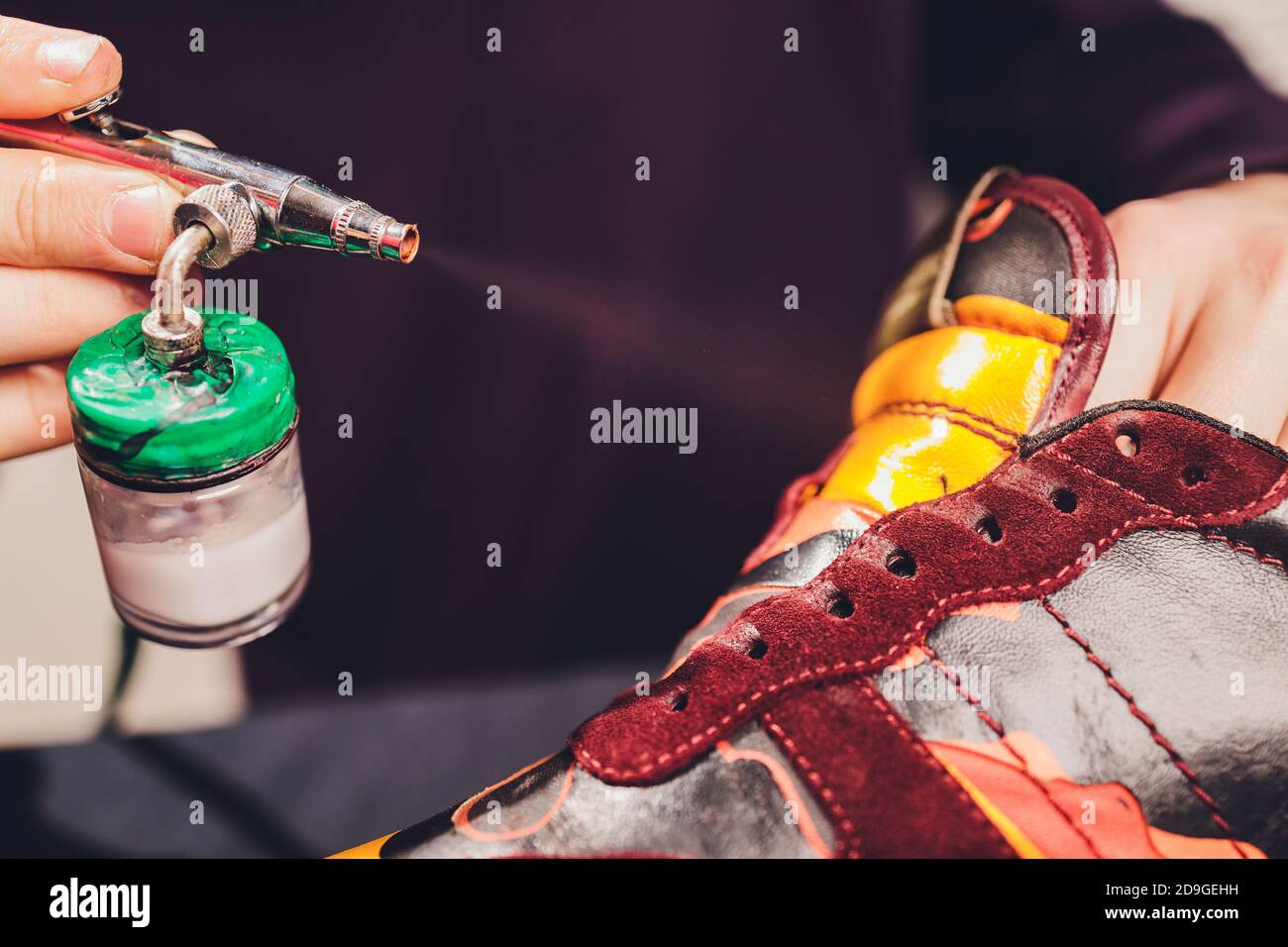 Craft man painting on a pair of shoes. Painting and restoring suede