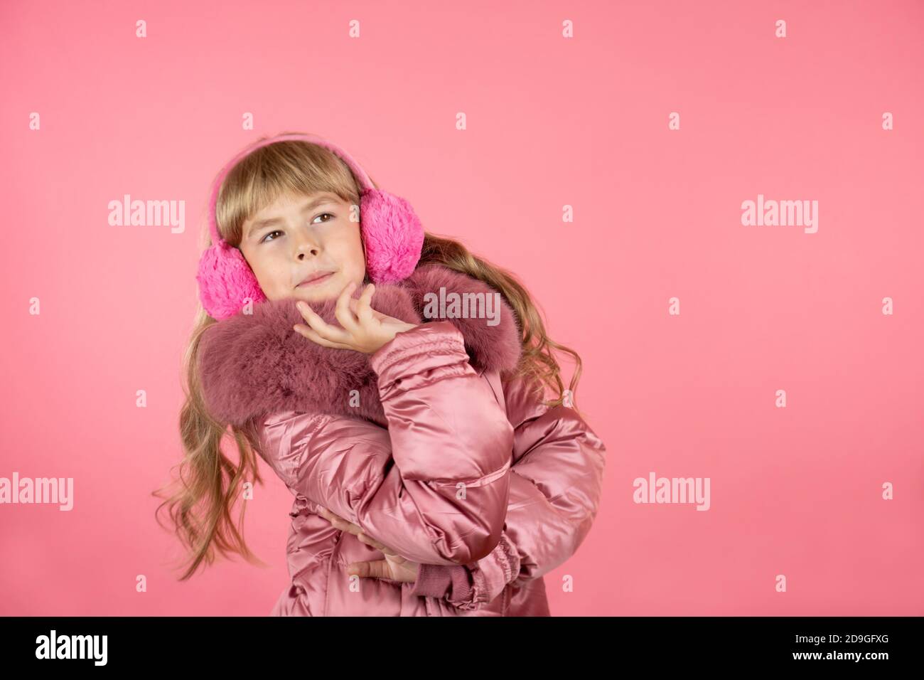 Little girl in a winter pink coat on a pink background. Stock Photo
