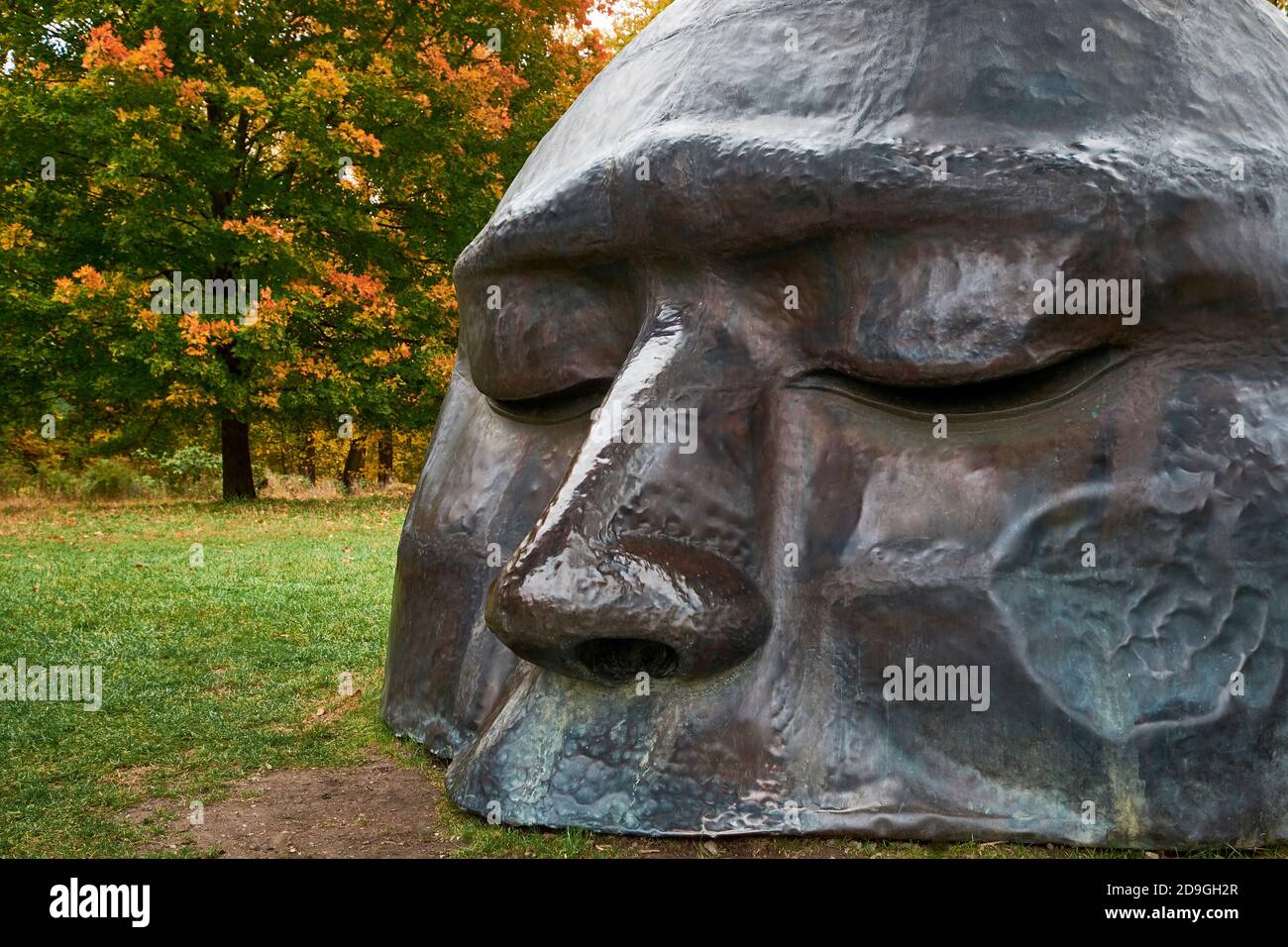 A closeup of the head in Zhang Huan's Three Legged Buddha sculpture. During autumn, peak fall color at Storm King Art Center in New York. Stock Photo