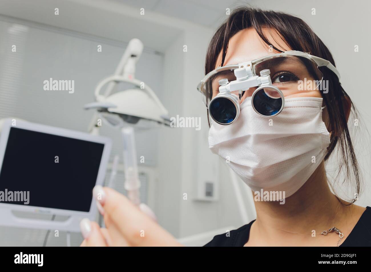 feMale dentist in special glasses with magnifying glasses and mask