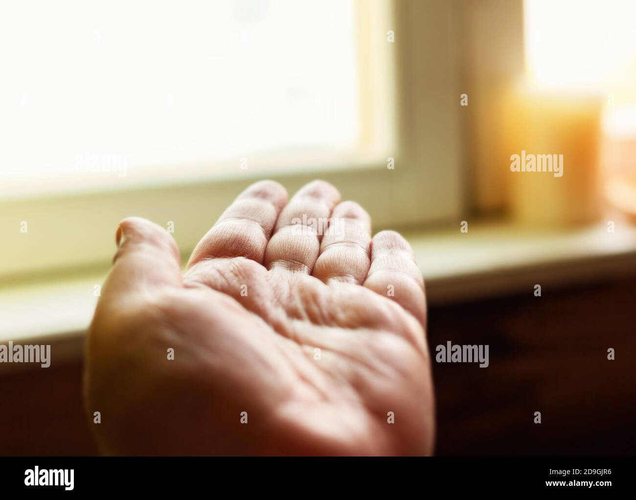 Open human hand is turned toward window at day Stock Photo