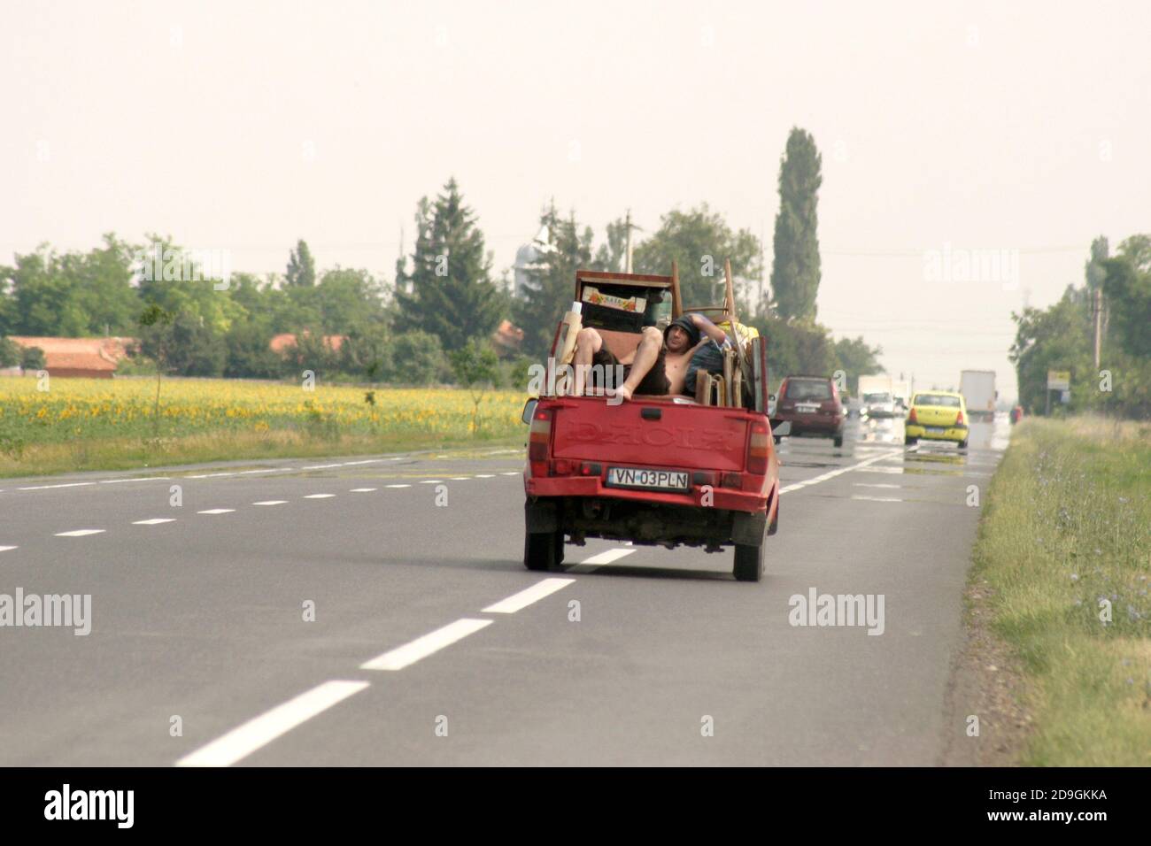 Man riding in the bed of a pickup truck on a road in Romania Stock